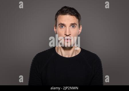 Eine Nahaufnahme eines verärgerten und schockierten Mannes sieht empört aus mit großen Augen und offenem Mund direkt in die Kamera Stockfoto