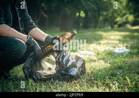 Ein Mann reinigt den Wald von Müll, dem Konzept der Pflege der Natur. Stockfoto