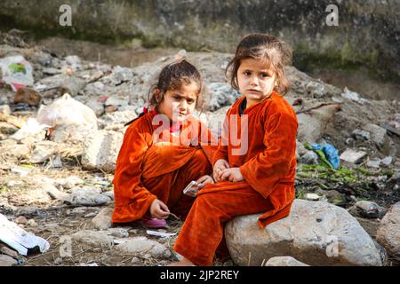 Obdachlose Kinder, die Hunger leiden und um Müll herum sitzen Stockfoto