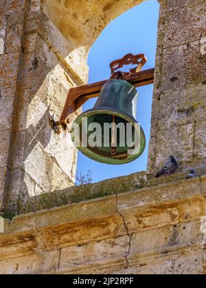 Glocke im mittelalterlichen Steinkirchturm mit blauem Himmel. Stockfoto