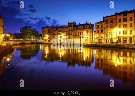 Stadt Bayonne in Frankreich in der Nacht mit Häusern der typischen Architektur und Reflexionen auf dem Fluss Adur. Europa. Stockfoto