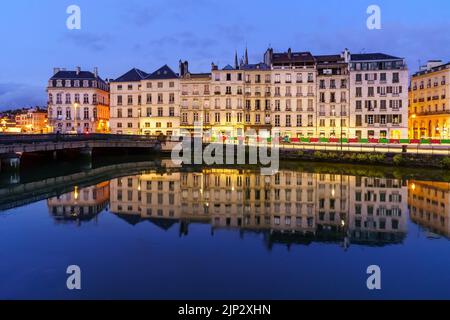 Stadt Bayonne in Frankreich in der Nacht mit Häusern der typischen Architektur und Reflexionen auf dem Fluss Adur. Europa. Stockfoto