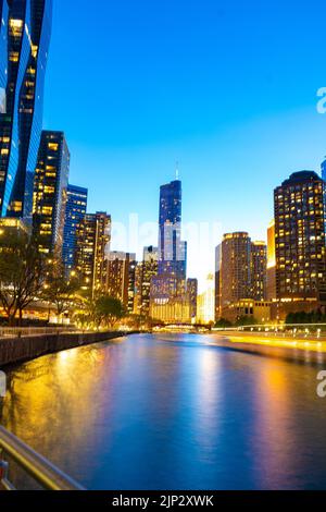 Eine vertikale Aufnahme von beleuchteten Gebäuden am Flussufer am Abend. Chicago, Usa. Stockfoto