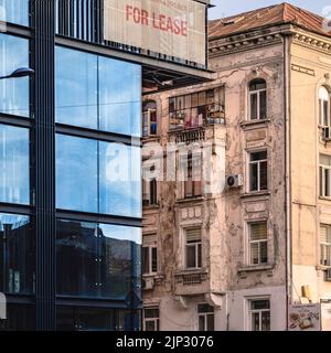 Ein Kontrast zwischen einem neuen Bürogebäude und einem alten Wohngebäude im Stadtzentrum von Bukarest Stockfoto