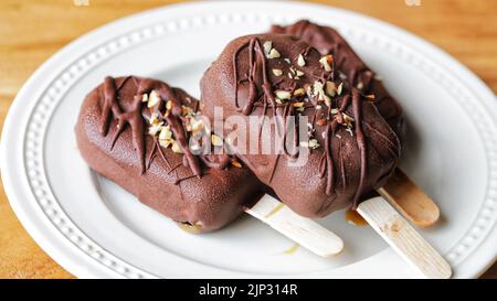 Ein paar leckere hausgemachte vegane Eisdielen, die mit Schokolade und Nüssen überzogen sind Stockfoto