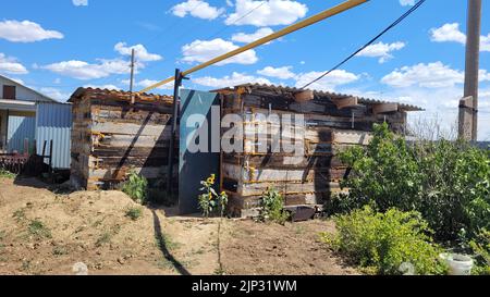 Garagenschuppen aus Eisenbahnsabeln. Kleines Nebengebäude in der Nähe eines privaten Hauses. Stockfoto