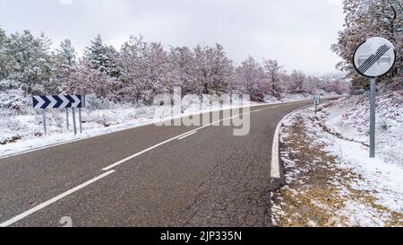 Asphaltstraße zum verschneiten Berg mit Verkehrsschildern erlaubt Überholen. Madrid. Stockfoto