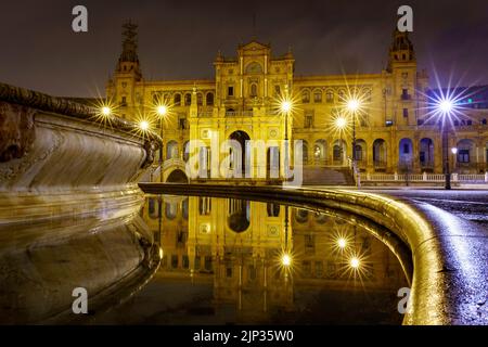 Plaza de España in Sevilla, Nachtszene nach Regen mit Langzeitbelichtung Foto und Reflexionen von Lichtern im Wasser und gepflasterten Straßen. Andalusien. Stockfoto