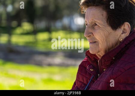 90-jährige weiße Frau im Park lachend und nachdenklich. Stockfoto