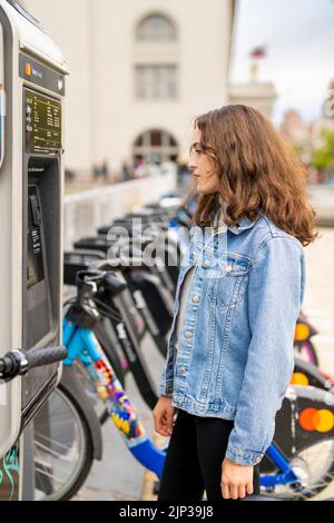 Junge Frau, die ein E-Bike mietet | Fahrradverleih | Transport | Fahrradverleih | ungestellte Porträts Stockfoto