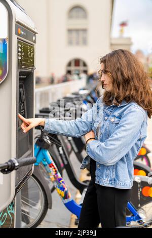 Junge Frau, die ein E-Bike mietet | Fahrradverleih | Transport | Fahrradverleih | ungestellte Porträts Stockfoto