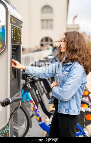 Junge Frau, die ein E-Bike mietet | Fahrradverleih | Transport | Fahrradverleih | ungestellte Porträts Stockfoto