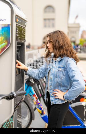 Junge Frau, die ein E-Bike mietet | Fahrradverleih | Transport | Fahrradverleih | ungestellte Porträts Stockfoto