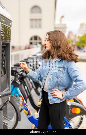 Junge Frau, die ein E-Bike mietet | Fahrradverleih | Transport | Fahrradverleih | ungestellte Porträts Stockfoto