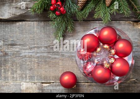 Postkartenmotiv im Vintage-Stil. Rote Weihnachtskugeln Dekorationen auf einem Holzhintergrund mit Kopierraum. Stockfoto