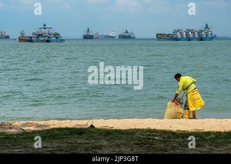 Am Strand im East Coast Park, Singapur, fegt ein Reiniger und räumt die Blätter ab. Speicherplatz Kopieren. Stockfoto