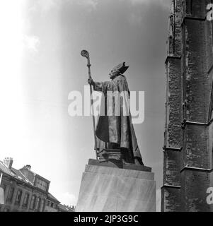 1960, historisch, Seitenansicht, von unten, eines Statuts von Égide Rombaux des katholischen Priesters Kardinal Mercier vor der St. Michael und Gudula Kathedrale, Brüssel, Belgien. E. Rombaux, 1941 ist auf dem Sockel eingeschrieben. Die Statue zeigt den Kardinal in voller Kleidung mit einem Stab, einem Crosier, mit einem gebogenen Oberteil, das ein Symbol des Guten Hirten ist. Desire-Joseph Mericer war bekannt für seinen heftigen Widerstand gegen die deutsche Besetzung des Landes im Jahr WW1, und als ein bekannter Gelehrter, verteilt einen Brief, Patriotismus und Ausdauer, nach der Invasion in allen seinen Kirchen gelesen werden. Stockfoto