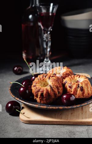Mini-Bündelkuchen mit Kirschen auf dunklem Hintergrund. Stockfoto