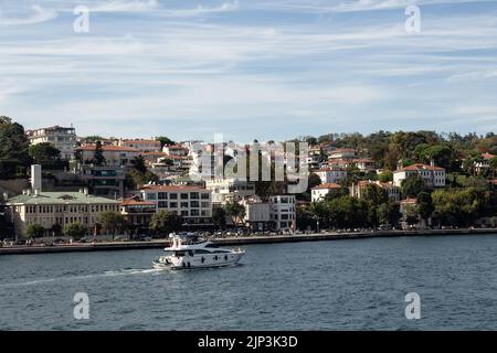 Blick auf eine Yacht, die auf dem Bosporus und dem Baltalimani-Viertel auf der europäischen Seite Istanbuls vorbeifährt. Es ist ein sonniger Sommertag. Wunderschöne Reiseszene. Stockfoto