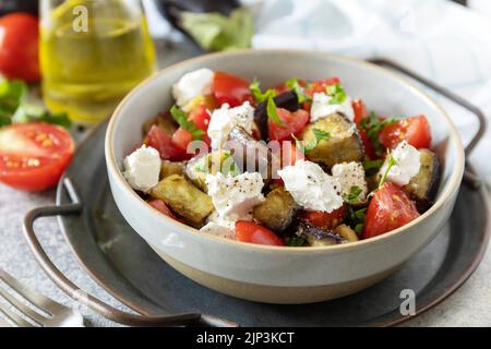 Gesunde vegetarische Ernährung. Salat mit gegrillten Auberginen, Tomaten und Feta-Käse auf einer grauen Steinplatte. Stockfoto