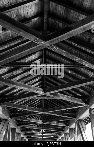 Eine vertikale Graustufenaufnahme eines langen Holzdachs von innen Stockfoto