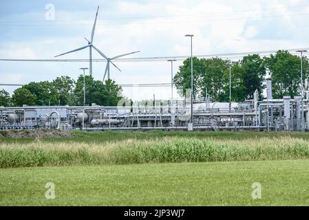 Ansicht einer Extraktionsstelle im Gasfeld mit Windturbinen im Hintergrund Stockfoto