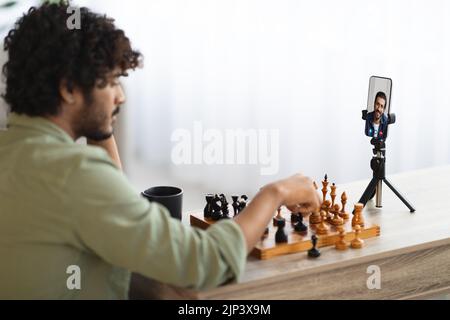 Eastern Mann spielt Schach mit seinem Freund per Videoanruf Stockfoto