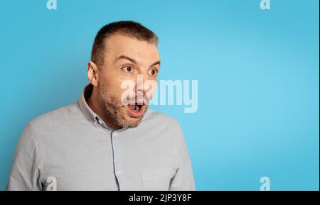 Schockierter Mann Mittleren Alters, Der Über Den Blauen Hintergrund Schaut Stockfoto