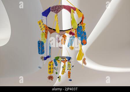 Verschiedene mehrfarbige Socken hängen an der weißen Decke mit Lichtern Stockfoto