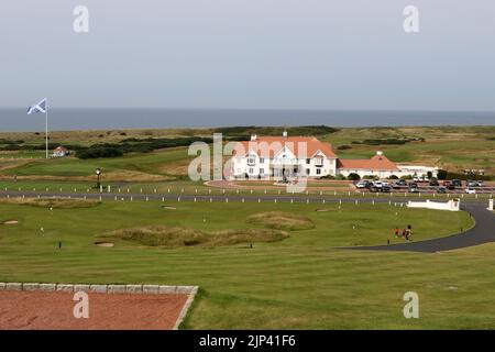Trump Turnberry, Ayrshire, Schottland Großbritannien.eine der größten Saltire-Flaggen in Schottland dominiert die Gegend und kann von Meilen entfernt gesehen werden. Dieser Blick vom Hotel Turnberry mit der Starterhütte für den ersten Tee, Übungsgreens und das 18. Green. Ebenfalls auf dem Foto ist die ikonische große Uhr zu sehen, die Donald Trumps Namen trägt. Das Gebäude auf dem Foto ist das Clubhaus Stockfoto