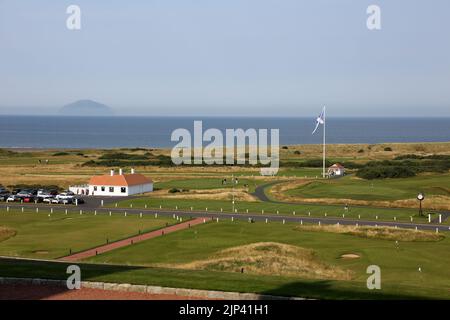 Trump Turnberry, Ayrshire, Schottland Großbritannien.eine der größten Saltire-Flaggen in Schottland dominiert die Gegend und kann von Meilen entfernt gesehen werden. Dieser Blick vom Hotel Turnberry mit der Starterhütte für den ersten Tee, Übungsgreens und das 18. Green. Ebenfalls auf dem Foto ist die ikonische große Uhr zu sehen, die den Namen Donald Trumps trägt. Am Horizont steht Ailsa Craig im Firth of Clyde Stockfoto