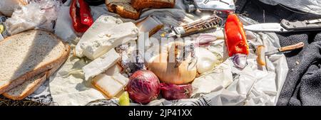 Rumänische traditionelle Küche mit Würstchen, Zwiebeln und Käse, Schinken und Paprika und einem Messer auf einem Handtuch Stockfoto