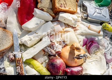 Rumänische traditionelle Küche mit Würstchen, Zwiebeln und Käse, Schinken und Paprika und einem Messer auf einem Handtuch Stockfoto