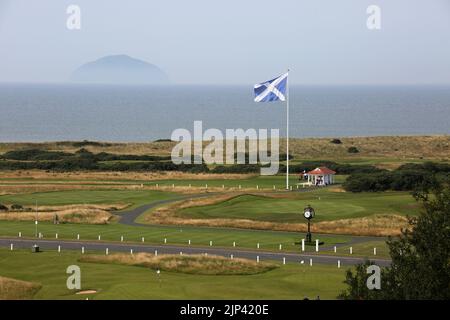 Trump Turnberry, Ayrshire, Schottland Großbritannien.eine der größten Saltire-Flaggen in Schottland dominiert die Gegend und kann von Meilen entfernt gesehen werden. Dieser Blick vom Hotel Turnberry mit der Starterhütte für den ersten Tee, Übungsgreens und das 18. Green. Ebenfalls auf dem Foto ist die ikonische große Uhr zu sehen, die den Namen Donald Trumps trägt. Am Horizont steht Ailsa Craig im Firth of Clyde Stockfoto