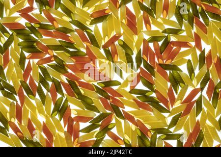 Dreifarbige Penne Pasta. Tomate, Spinat und Weizenpastas, Beleuchtung hinten Stockfoto