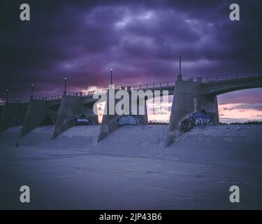 Eine Betonbrücke mit Graffiti-Wandkunst während eines wunderschönen Sonnenuntergangs Stockfoto