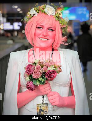 Persephone-Charakterkostüm aus dem Webcomic Lore Olympus, Cosplayerin posiert im Outfit mit rosa Haut und Haaren, MCM Comic Con London Stockfoto