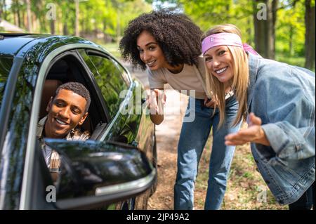 Zwei junge Frauen im Gespräch mit dem Mann im Auto Stockfoto