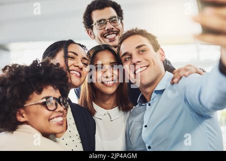 Lustige, vereinte Kollegen machen ein Selfie mit einem Handy, das aufgeregt, glücklich oder motiviert ist und bereit ist, das Startup-Geschäft an die Spitze zu bringen. Lächelnd, glücklich Stockfoto