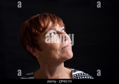 Gesicht einer Frau mittleren Alters auf schwarzem Hintergrund Stockfoto