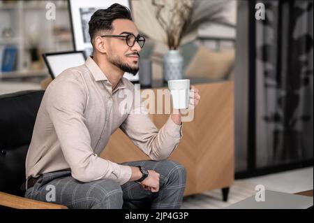 Meditierender Mann mit Kaffee, der seitlich zur Kamera sitzt Stockfoto