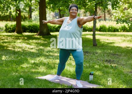 Porträt einer übergewichtigen schwarzen Frau, die im Park im Freien arbeitet und lächelt und den Platz kopiert Stockfoto