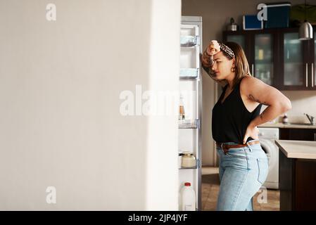 Plus Größe, mollige und hungrige Frau in einem Kühlschrank suchen, denken an Nahrung oder auf der Suche nach einer Mahlzeit, während auf einer Diät. Gestresste, ängstliche und frustrierte Dame Stockfoto