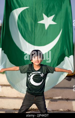 Kleiner Patriot Junge steht und genießt mit der Flagge Pakistans. Unabhängigkeitstag Pakistan Konzept. Stockfoto