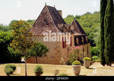 Ein schönes Beispiel für ein Landhaus in der Region Perigord Noir der Dordogne. Es ist aus honigfarbenem Stein mit einem steil abfallenden Dach gebaut. Stockfoto