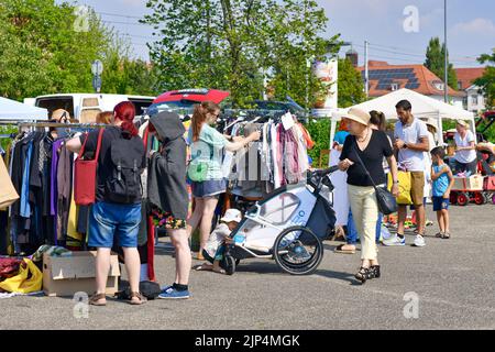 Heidelberg, Deutschland - August 2022: Menschen schauen auf dem Flohmarkt mit alten Second-Hand-Kleidern durch das Regal Stockfoto