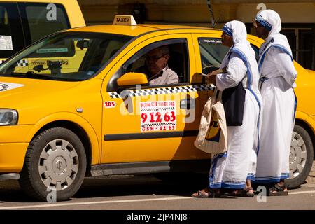 Afrikanische Nonnen in weißen Gewändern, die in Sofia, Bulgarien, Osteuropa, dem Balkan und der EU um Fahrgeld für ein gelbes Taxi baten Stockfoto