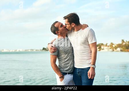 Küsse am Strand sind das, wofür sie leben. Ein liebevolles reifes Paar, das den Tag am Strand verbringt. Stockfoto