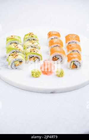 Sushi-Rollen auf Platte, heller Hintergrund. Serviert mit Wasabi und Ingwer. Verschiedene japanische Sushi. Traditionelles Essen. Stockfoto
