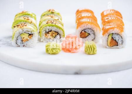 Sushi-Rollen auf Platte, heller Hintergrund. Serviert mit Wasabi und Ingwer. Verschiedene japanische Sushi. Traditionelles Essen. Stockfoto